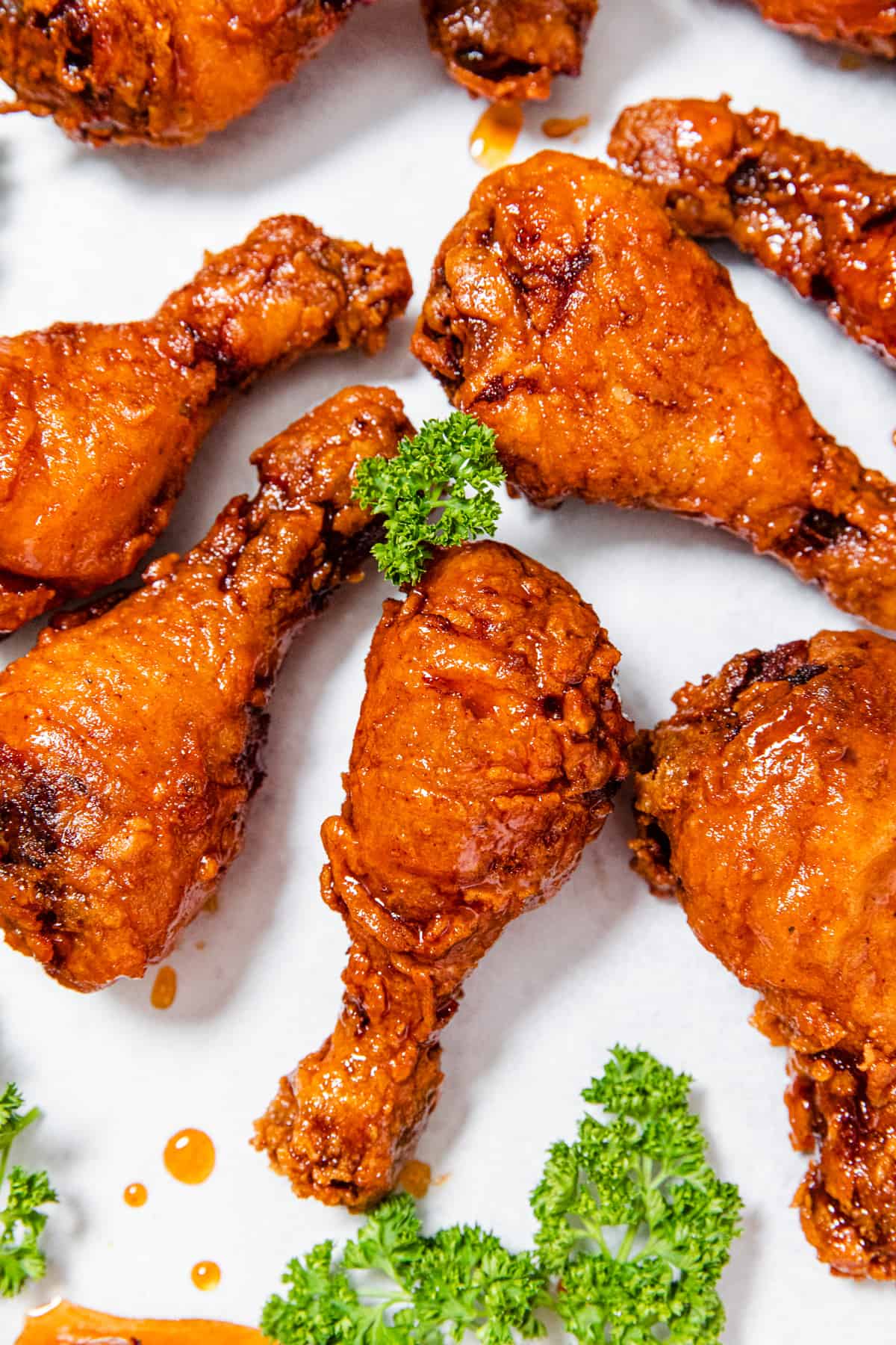 multiple fried chicken pieces on parchment paper with curly parsley around it