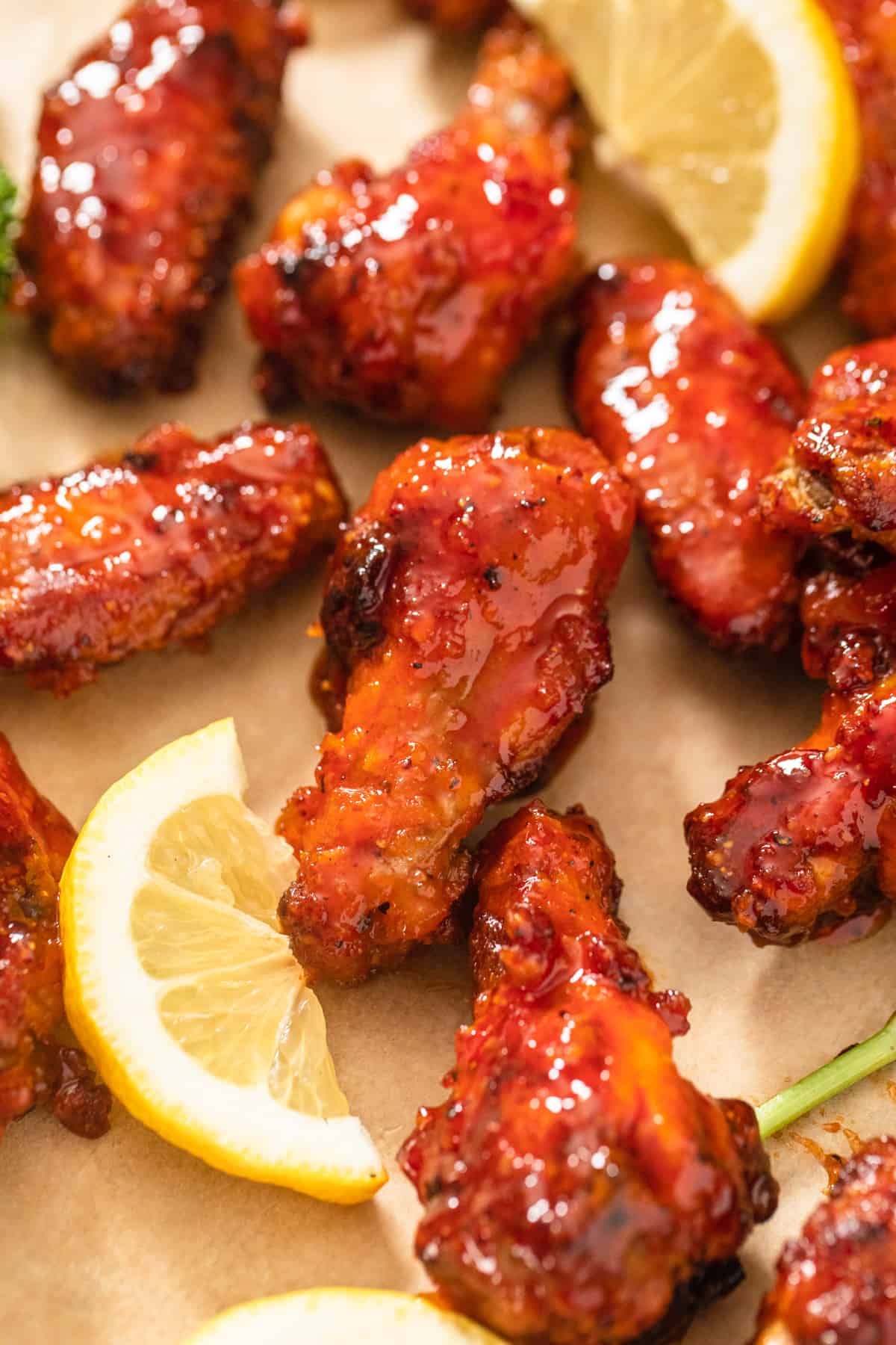 chicken wings on a brown parchment paper sheet with lemon slices beside them