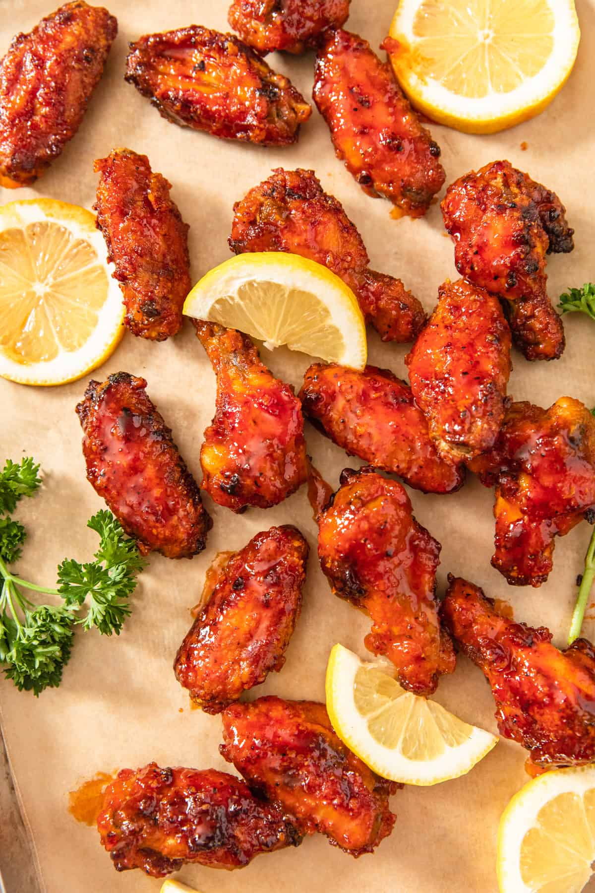 chicken wings on a sheet of parchment paper with lemon slices around them