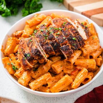 sliced chicken breast on a plate of pasta