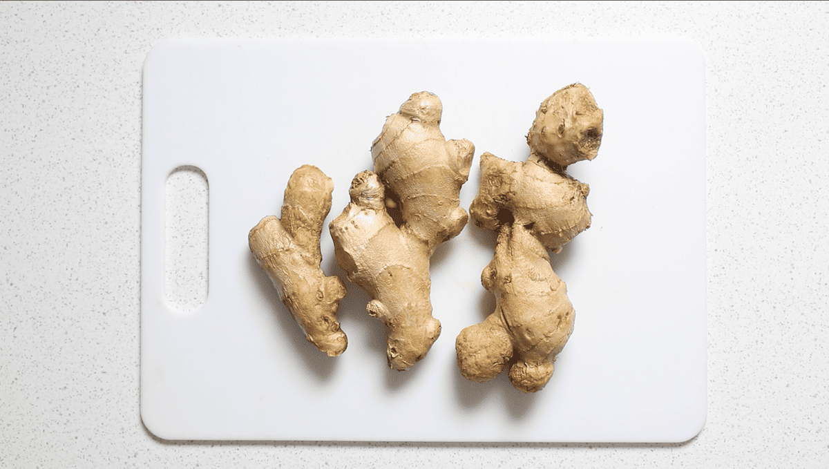 three ginger roots on a white cutting board