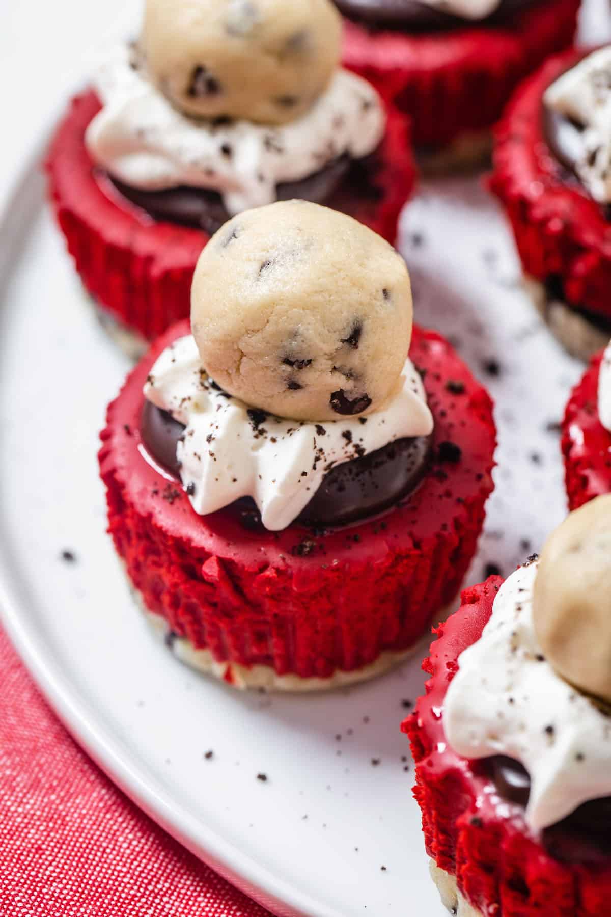 close up of platter of mini red velvet cheesecakes topped with cookie dough