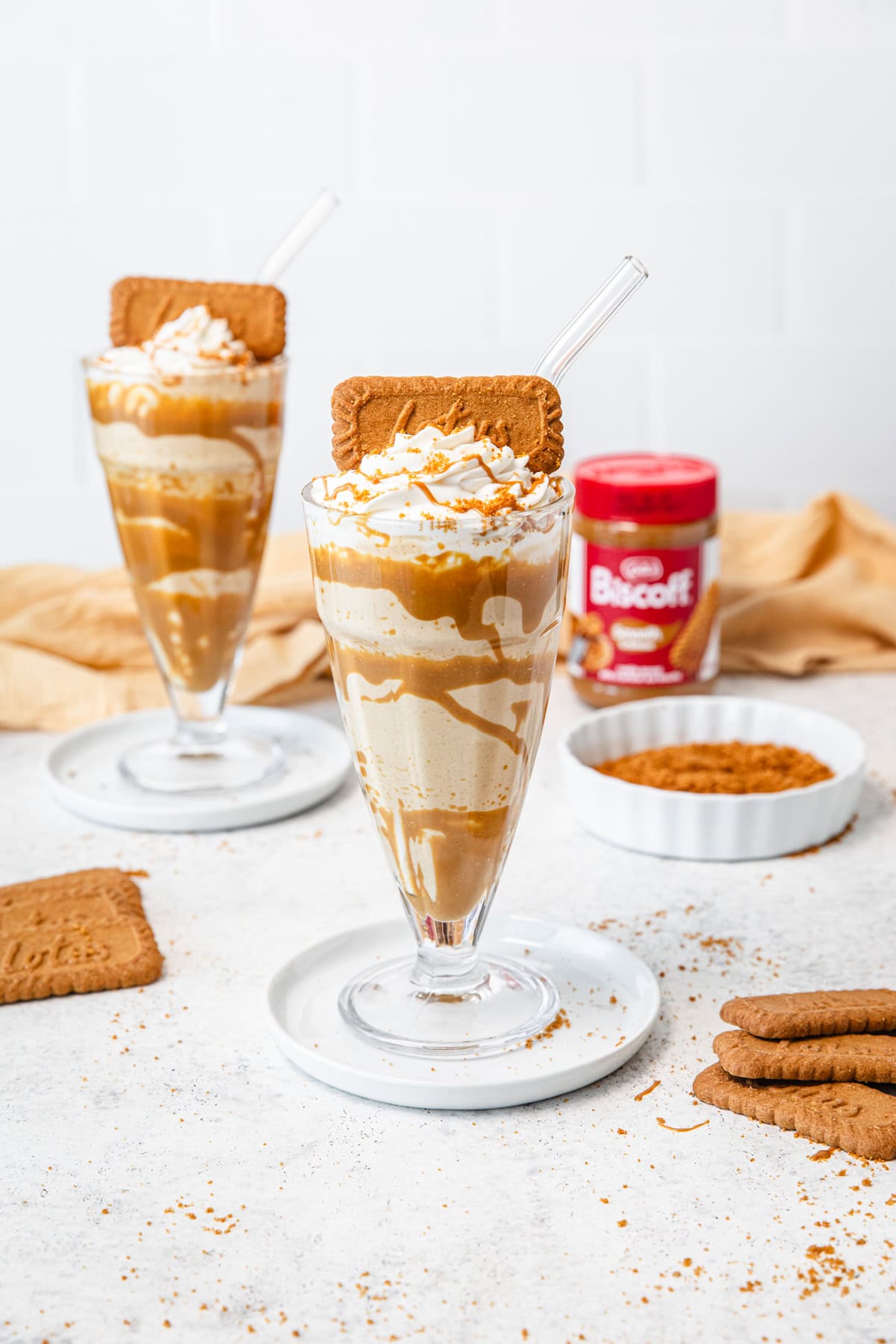 Two milkshakes with Biscoff cookies and Biscoff cookie butter around them