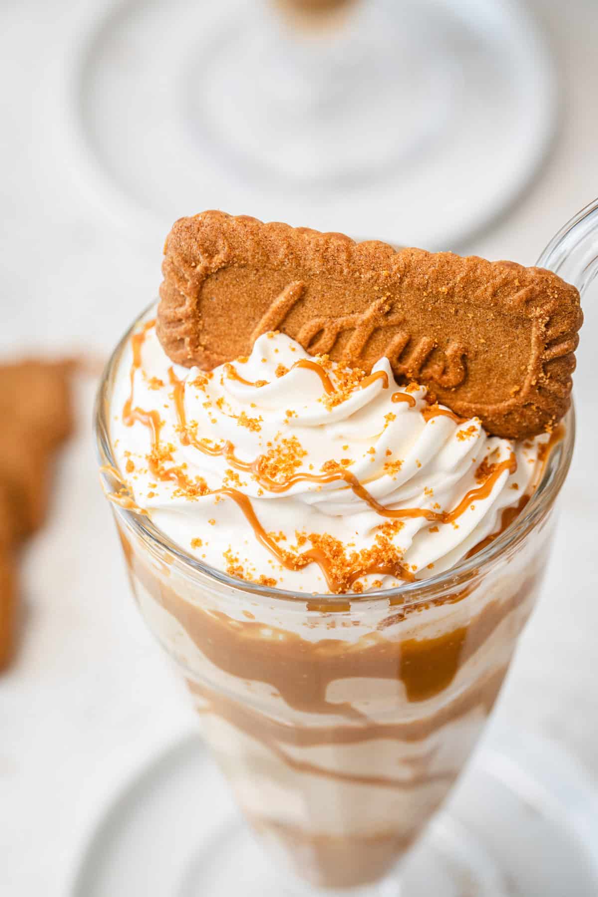 top angled close up of milkshake topped with whipped cream and a biscuit