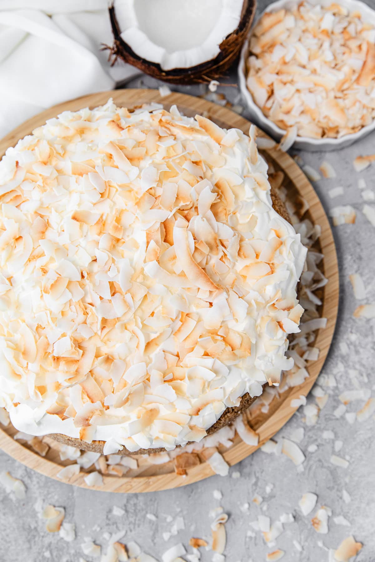 top of cheesecake with whipped cream and toasted coconut on top, and halved coconut around it